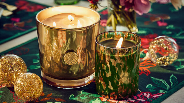 Two lit candles sitting on decorated tablescape